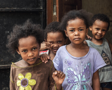 Four young children standing near a doorway