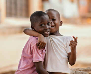 Two boys smiling and hugging outdoors