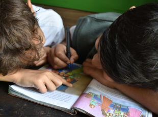 Two children reading and drawing in illustrated book
