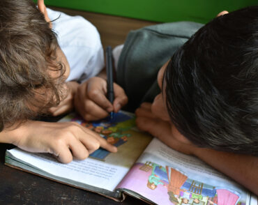 Two children reading and drawing in illustrated book