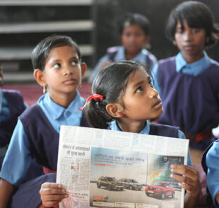Schoolchildren in classroom reading a newspaper