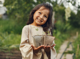 Smiling girl holding seedlings in garden