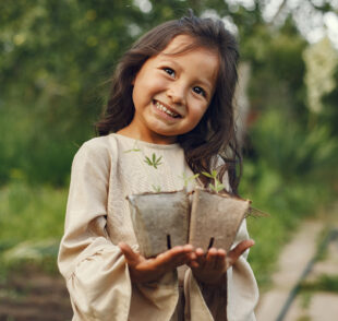 Smiling girl holding seedlings in garden