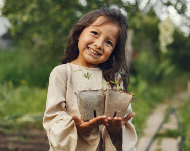 Smiling girl holding seedlings in garden